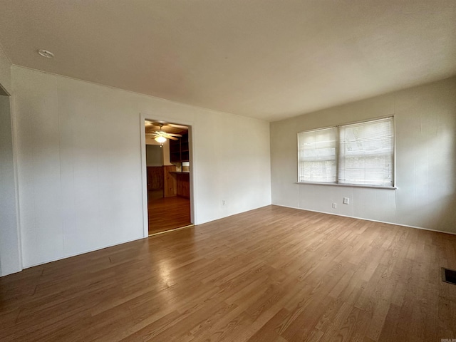 empty room featuring wood finished floors, visible vents, and ceiling fan