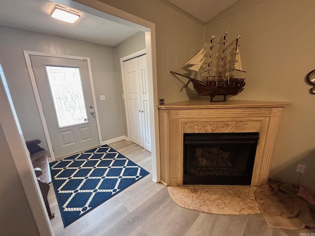 foyer entrance with a high end fireplace, baseboards, and wood finished floors