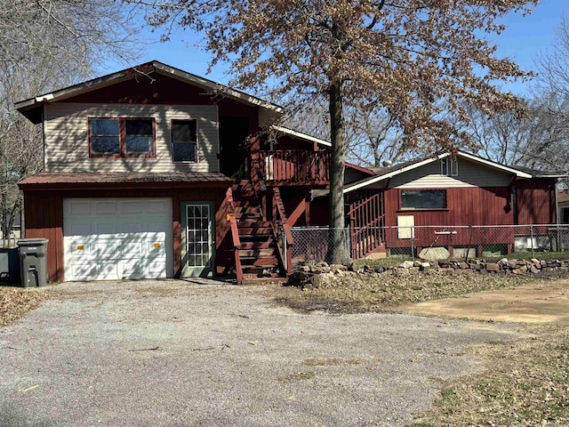 view of front of house with stairway, driveway, a garage, and fence