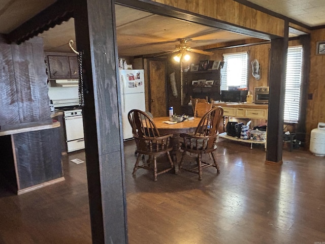 dining space with ceiling fan, wood finished floors, beam ceiling, and wood walls