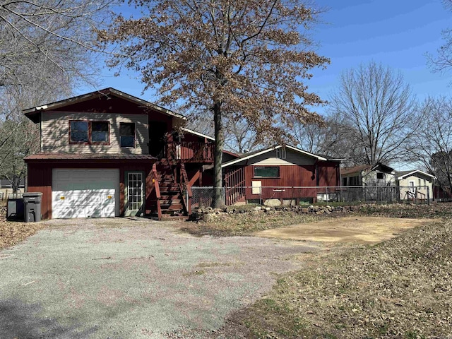 view of front of house with aphalt driveway, stairway, a garage, and fence