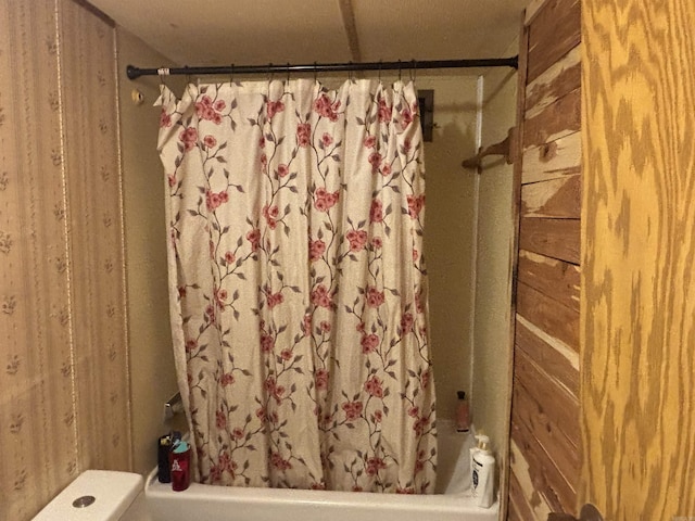 bathroom featuring wood walls and shower / bath combo with shower curtain