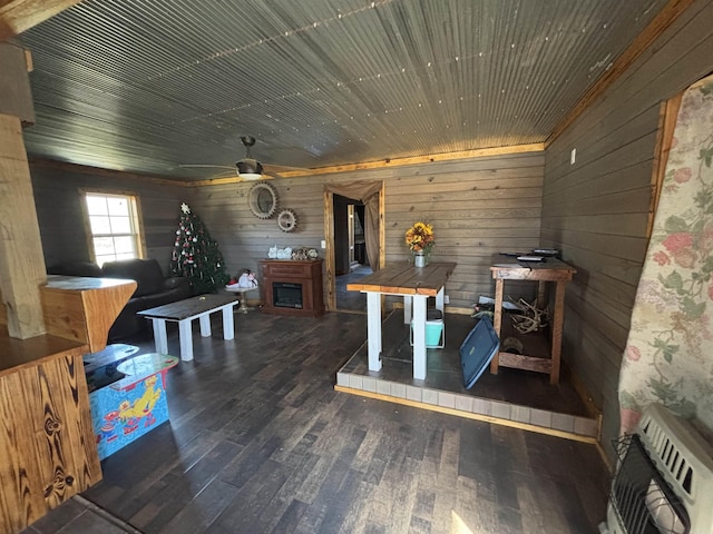 interior space featuring ceiling fan, wood walls, a fireplace, wood finished floors, and heating unit