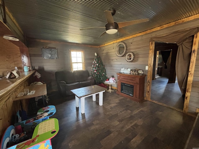 living room with a fireplace, wooden walls, wood finished floors, and ceiling fan