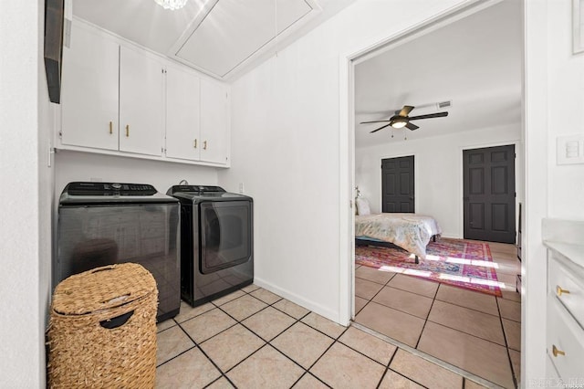 clothes washing area featuring baseboards, washing machine and dryer, attic access, light tile patterned floors, and cabinet space