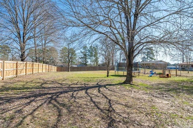 view of yard featuring playground community, a trampoline, and a fenced backyard