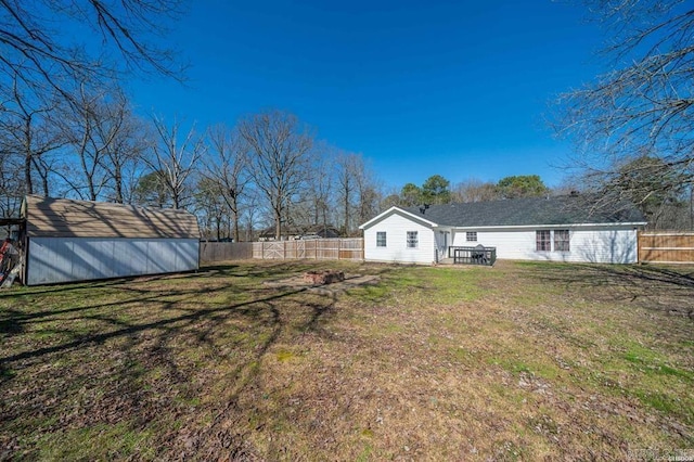 view of yard featuring an outdoor structure, a fenced backyard, and a shed