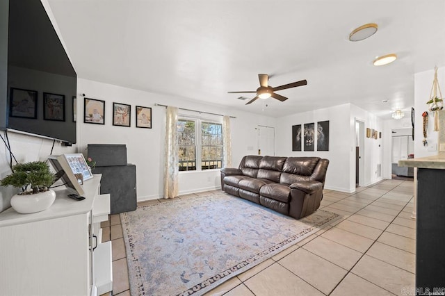 living room featuring light tile patterned floors, baseboards, and a ceiling fan