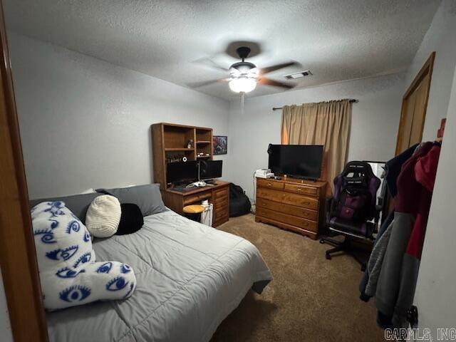 carpeted bedroom with visible vents, a textured ceiling, and a ceiling fan