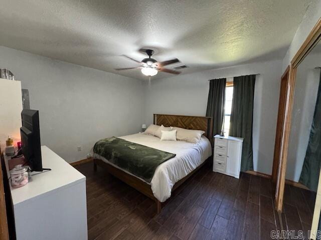 bedroom featuring dark wood-type flooring, a ceiling fan, visible vents, and a textured ceiling