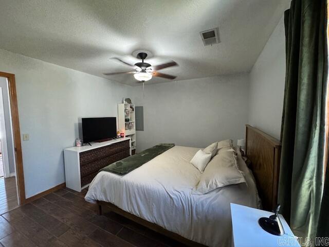 bedroom with a ceiling fan, dark wood-style floors, visible vents, baseboards, and a textured ceiling