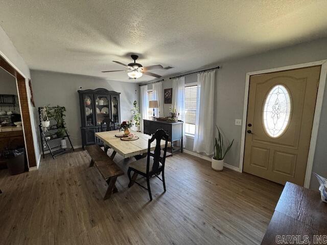 dining space with baseboards, a textured ceiling, a ceiling fan, and wood finished floors