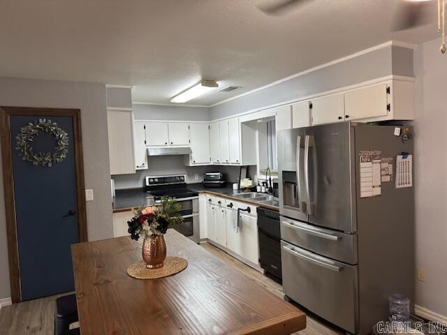 kitchen with dark countertops, white cabinets, stainless steel appliances, and a sink