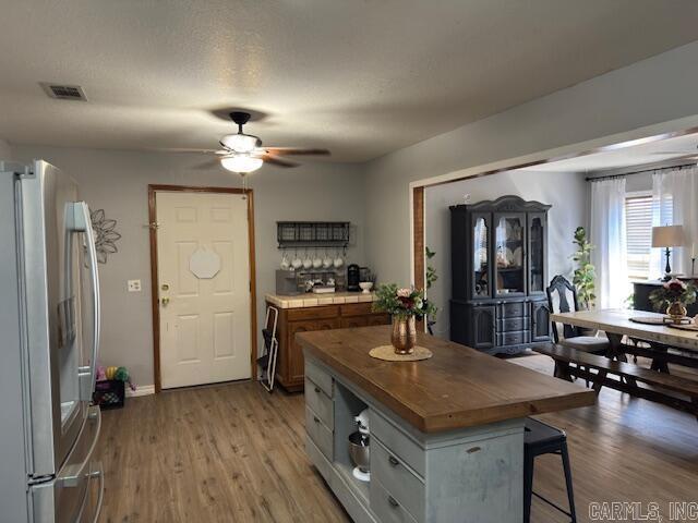 kitchen with a breakfast bar, light wood finished floors, visible vents, and freestanding refrigerator