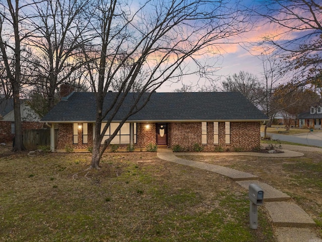 ranch-style house featuring brick siding, a chimney, roof with shingles, and fence