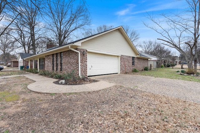 view of home's exterior with a garage, driveway, brick siding, and a chimney