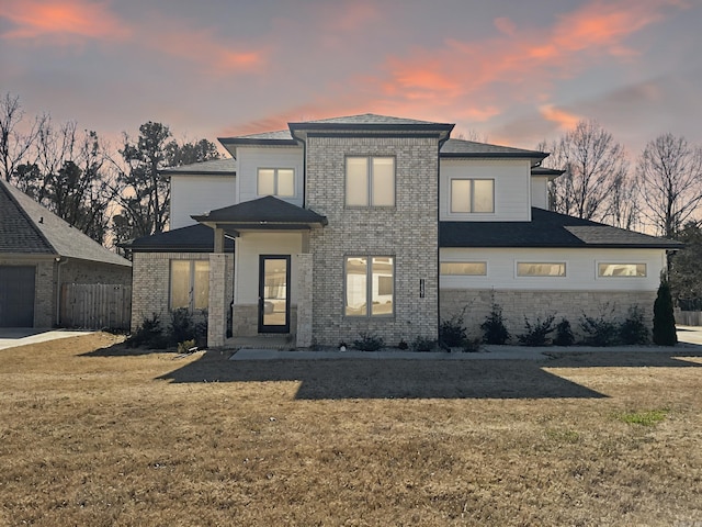 view of front facade with a front yard, fence, and brick siding