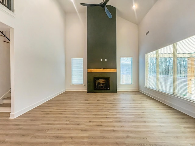 unfurnished living room featuring stairway, a fireplace, high vaulted ceiling, and visible vents