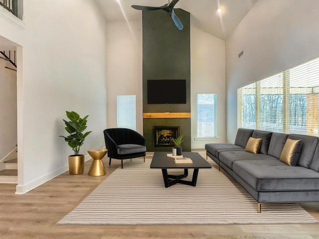 living room with baseboards, high vaulted ceiling, wood finished floors, and a fireplace