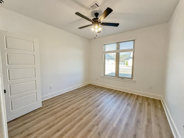 spare room with visible vents, baseboards, and wood finished floors