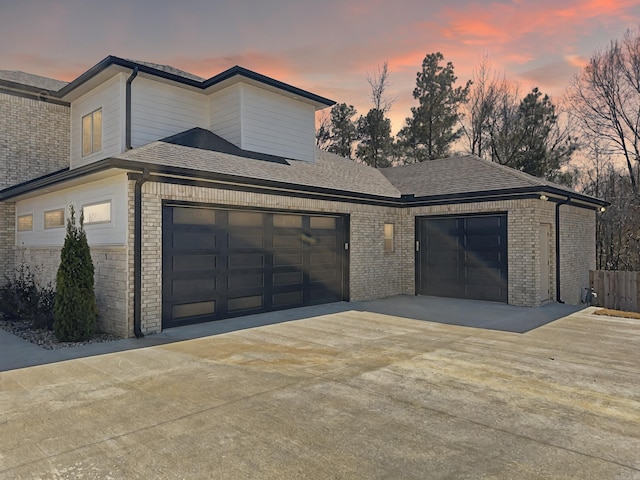 exterior space with brick siding, driveway, a shingled roof, and a garage