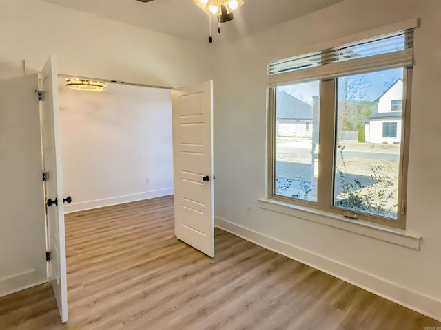 unfurnished room featuring ceiling fan, baseboards, and light wood-style floors