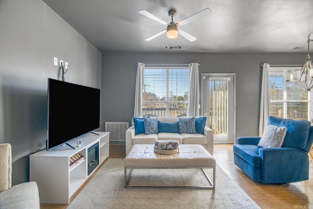 living area featuring a wealth of natural light, visible vents, and wood finished floors