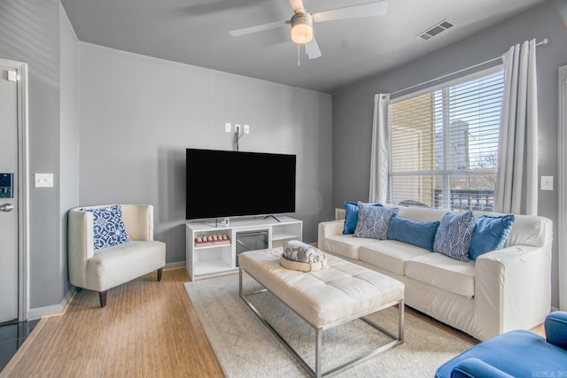 living room featuring baseboards, wood finished floors, visible vents, and ceiling fan