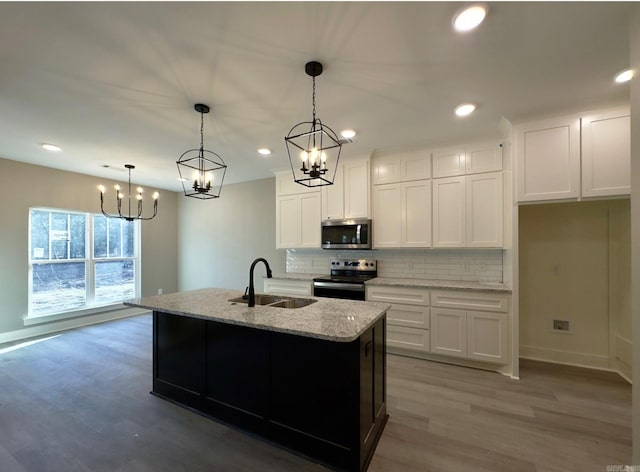 kitchen featuring a sink, appliances with stainless steel finishes, white cabinetry, light wood-type flooring, and backsplash