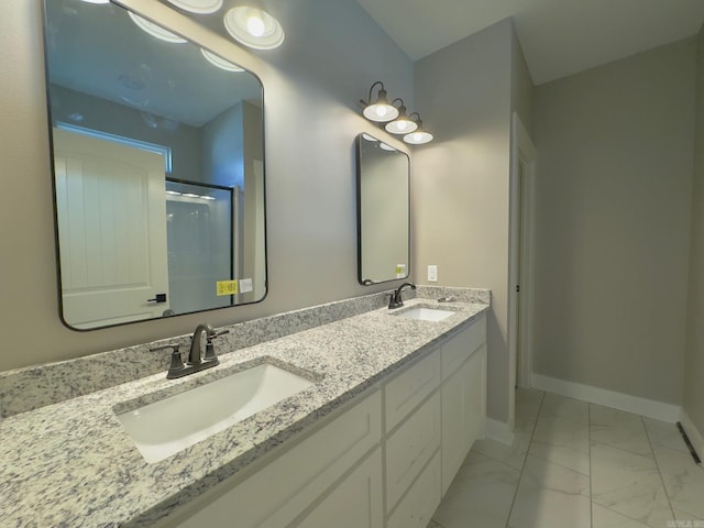 full bath featuring a sink, baseboards, marble finish floor, and a shower with door