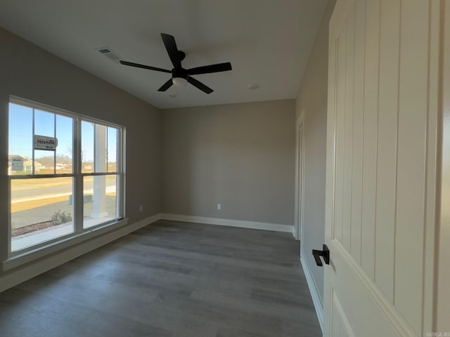 spare room with visible vents, baseboards, dark wood finished floors, and a ceiling fan