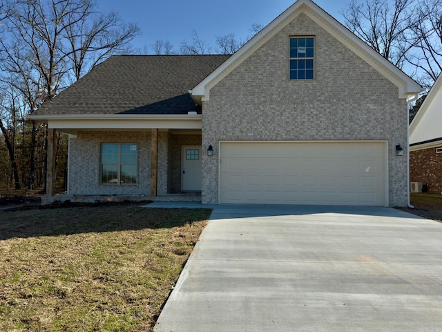 view of front of home featuring a front yard, concrete driveway, an attached garage, and a shingled roof