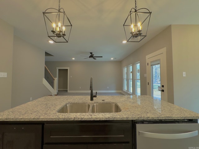 kitchen featuring a sink, open floor plan, dishwasher, light stone counters, and a kitchen island with sink