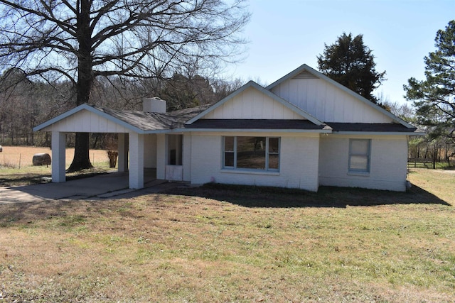 view of front of home featuring an attached carport, a front yard, fence, a chimney, and brick siding