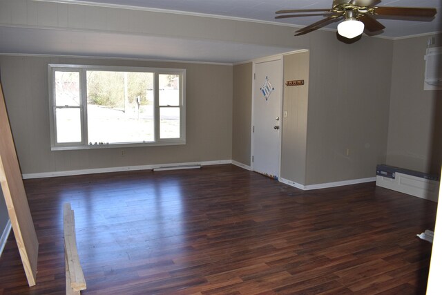 spare room featuring ceiling fan, baseboards, dark wood-style floors, and crown molding