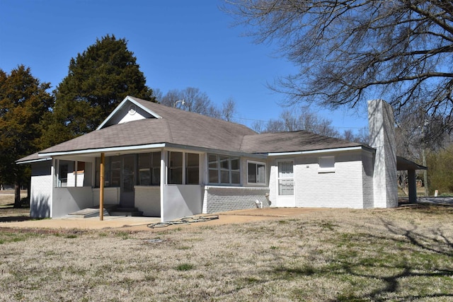 back of property with a lawn, brick siding, and a sunroom