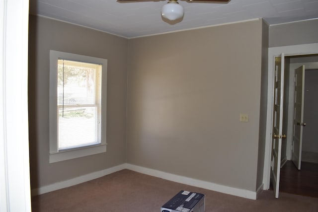 carpeted spare room with a ceiling fan and baseboards