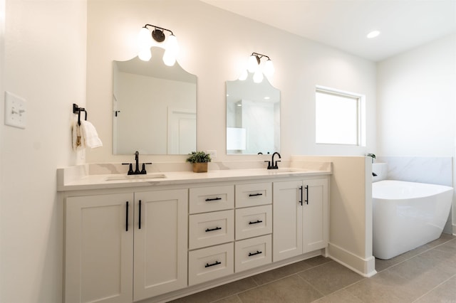 bathroom featuring tile patterned flooring, double vanity, a soaking tub, and a sink