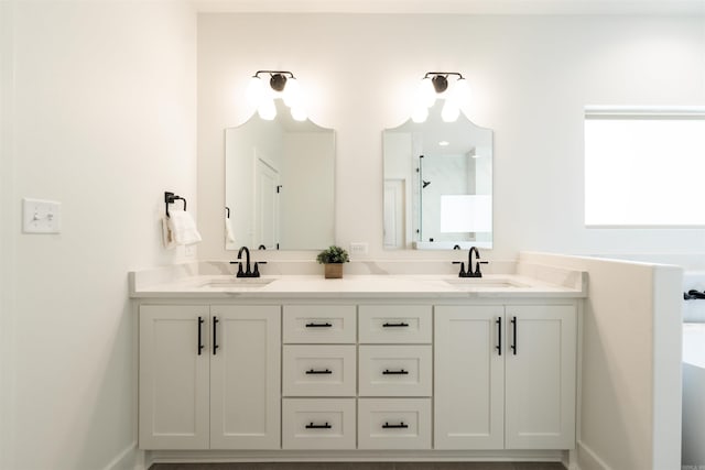 bathroom with double vanity, a shower, baseboards, and a sink