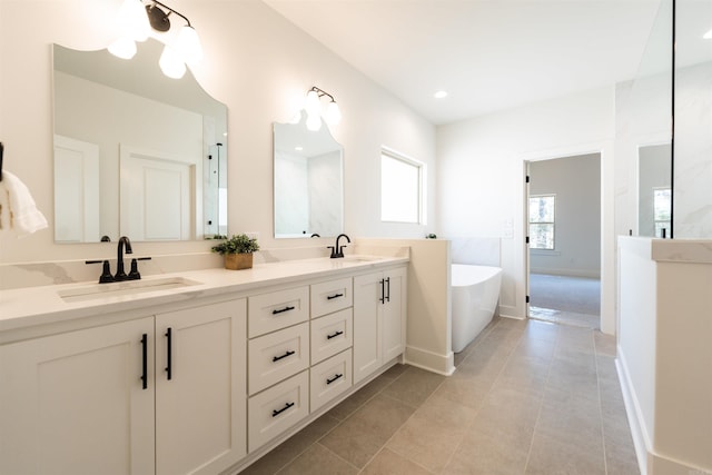 bathroom with double vanity, tile patterned floors, a freestanding bath, and a sink