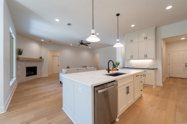 kitchen featuring white cabinetry, light wood-style flooring, a sink, stainless steel dishwasher, and open floor plan