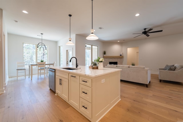 kitchen with light stone counters, light wood-style floors, open floor plan, and a sink