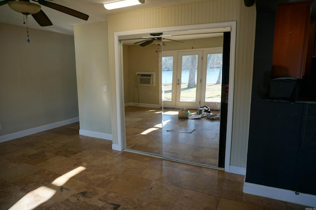 empty room featuring french doors, a ceiling fan, a wall mounted AC, and baseboards