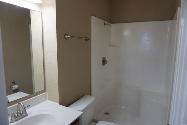 bathroom featuring toilet, walk in shower, and vanity