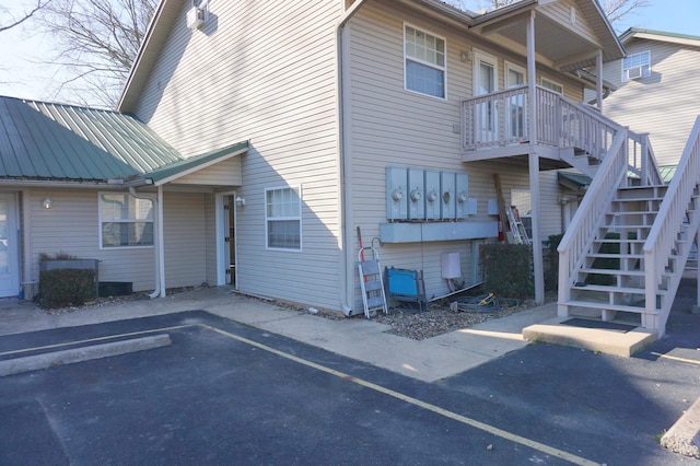 view of side of property with metal roof, stairs, and uncovered parking