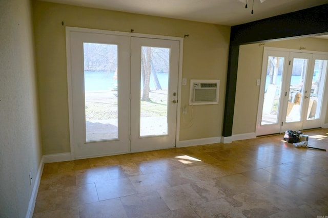 doorway to outside featuring a healthy amount of sunlight, french doors, a wall mounted AC, and baseboards