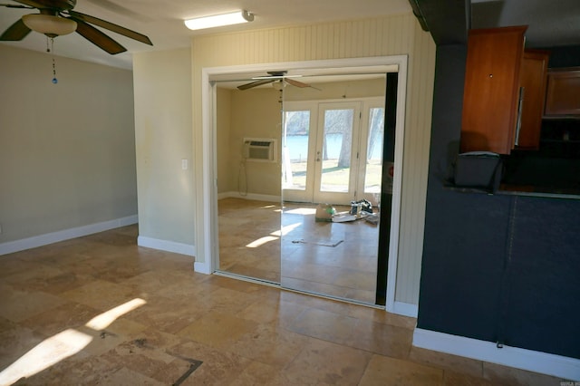 empty room featuring a wall unit AC, a ceiling fan, baseboards, and french doors