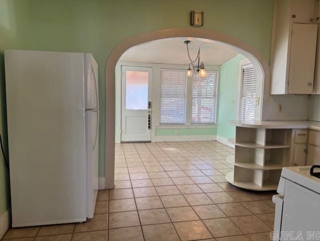 kitchen with open shelves, light countertops, freestanding refrigerator, arched walkways, and range