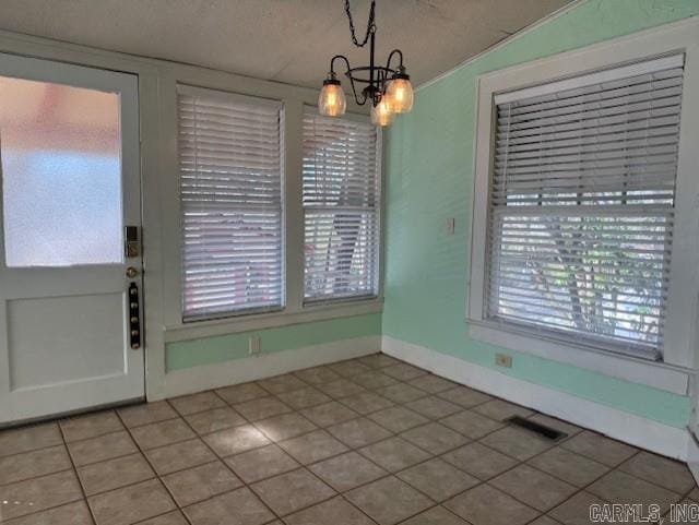 unfurnished dining area with light tile patterned flooring, baseboards, visible vents, and a chandelier