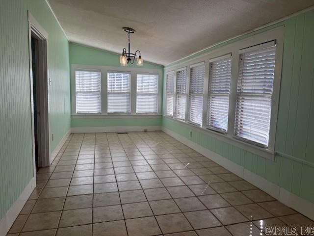 unfurnished dining area with tile patterned floors, lofted ceiling, and a chandelier